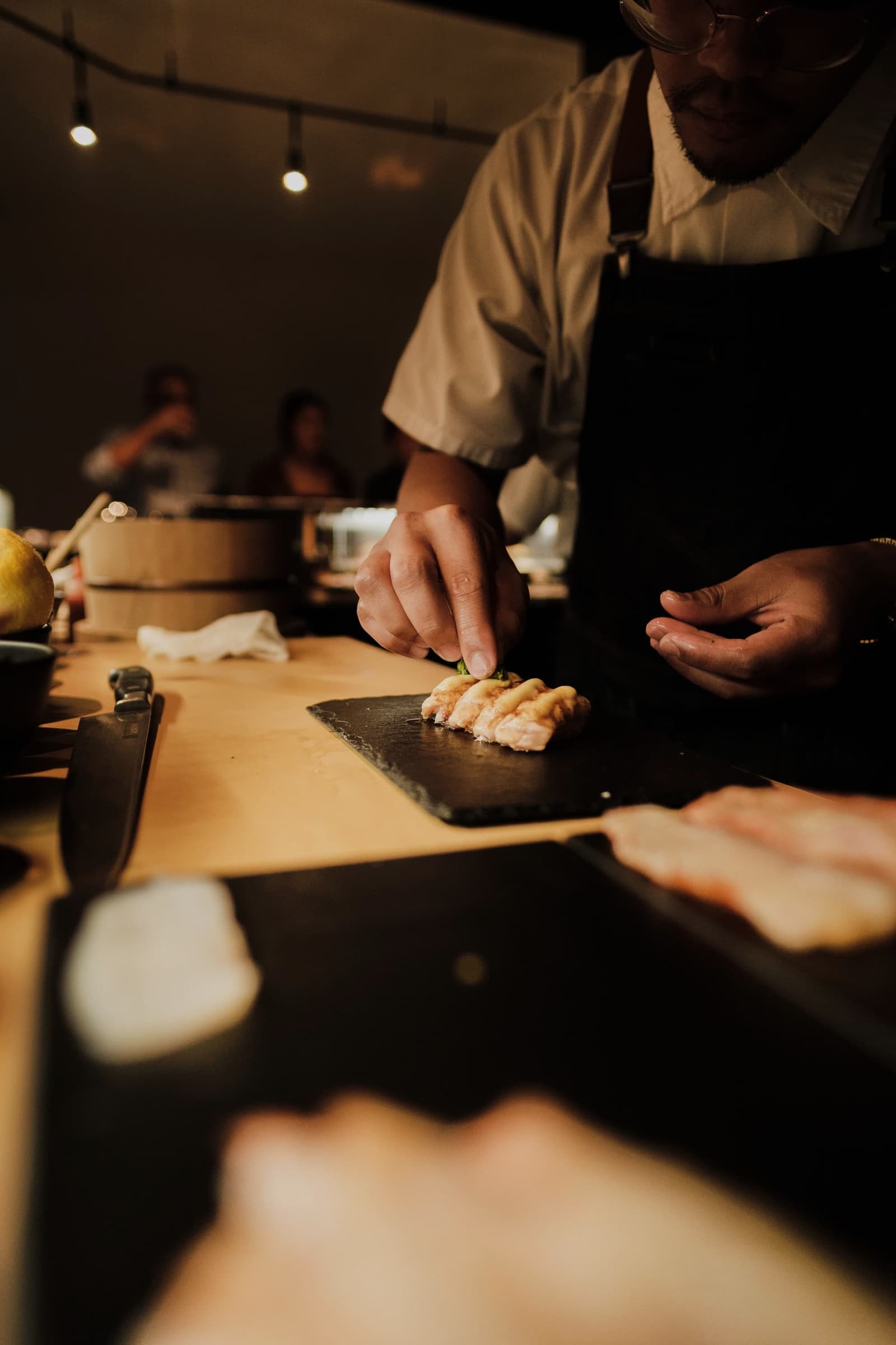 A chef pressing nigiri at a dark counter