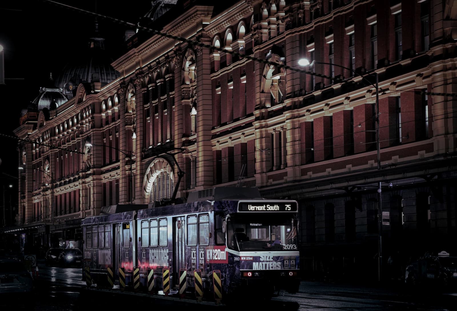A tram passing Flinders Street at night