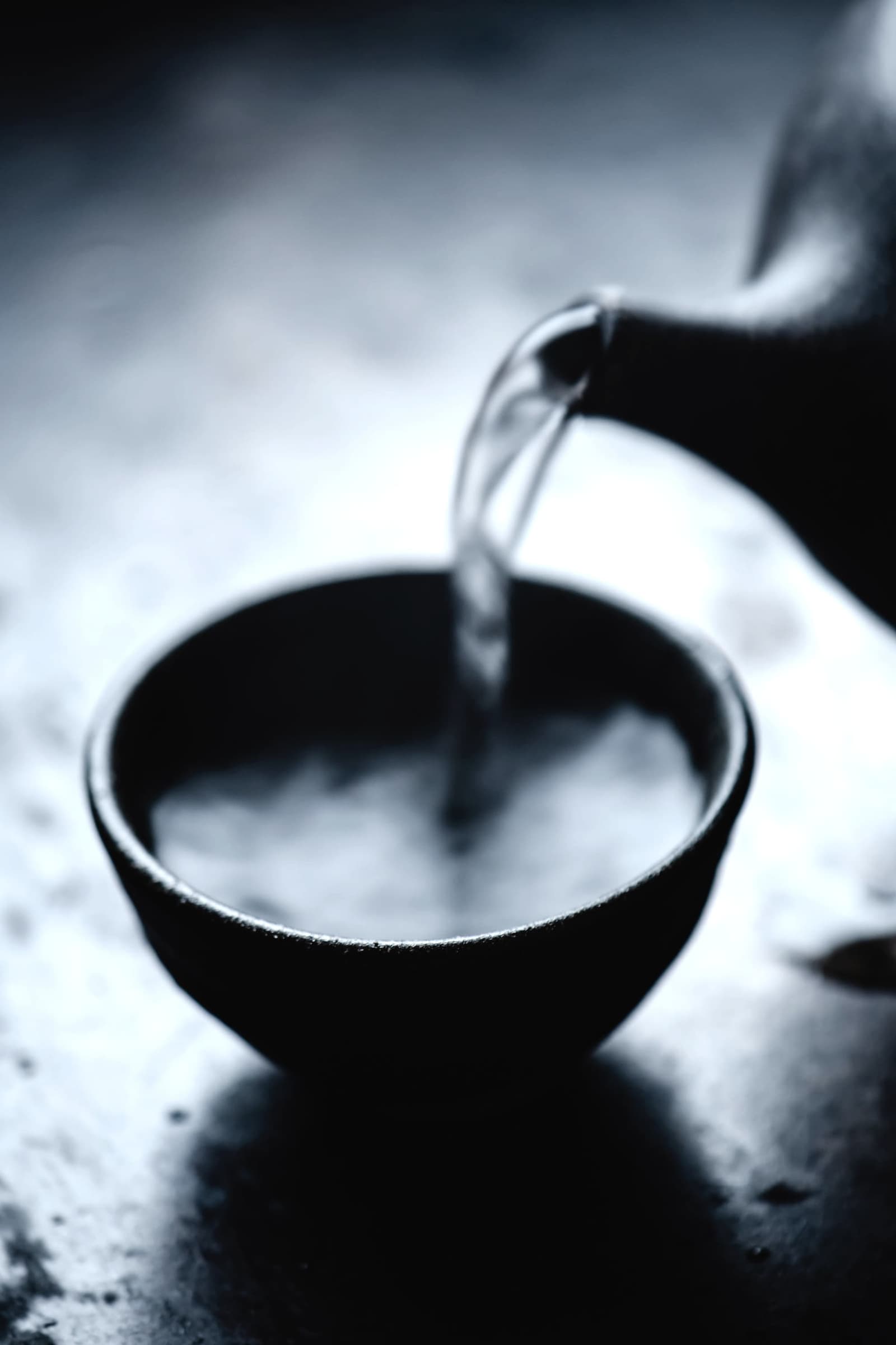 Sake poured from a flask into a dark cup