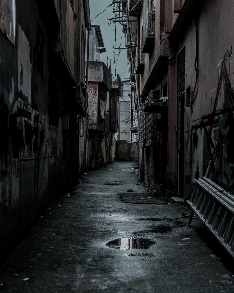 A narrow lane at night, wet underfoot